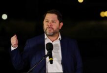 Man in a suit delivering a speech at an outdoor event