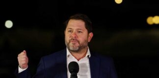 Man in a suit delivering a speech at an outdoor event