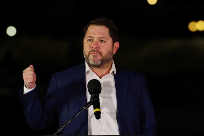 Man in a suit delivering a speech at an outdoor event