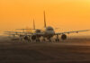 Airplanes lined up on a runway during sunset