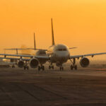Airplanes lined up on a runway during sunset