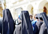 Group of nuns in black attire gathered outdoors, one holding a megaphone