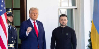 Two men standing near flags and a guard