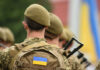 Soldiers in uniform with Ukrainian flag patches.