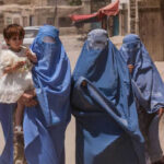 Three women in burqas walking with a child