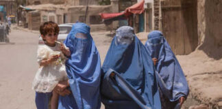 Three women in burqas walking with a child
