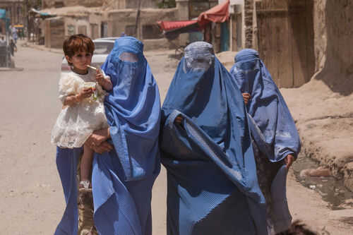 Three women in burqas walking with a child