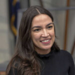 Rogan SLAMS AOC’s ‘Weird’ Billionaire Claim A person smiling, wearing a black shirt.