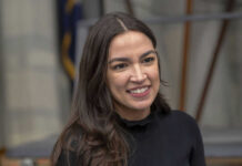 Rogan SLAMS AOC’s ‘Weird’ Billionaire Claim A person smiling, wearing a black shirt.