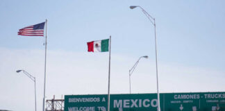 Border crossing sign to Mexico with U.S. and Mexican flags
