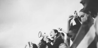 Group of diverse individuals participating in a protest with a megaphone and flags