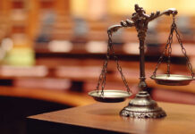 Judge BANNED for Life After HANDCUFFING Lawyer Close-up of a decorative scales of justice in a courtroom setting