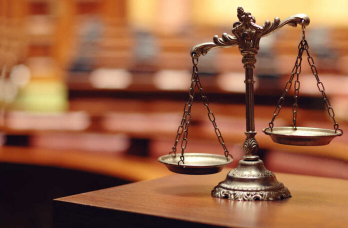 shutterstock_140867215.jpg Close-up of a decorative scales of justice in a courtroom setting