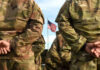 Soldiers standing in formation with an American flag in the background
