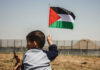 Child holding a Palestinian flag in an outdoor area