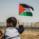Child holding a Palestinian flag in an outdoor area