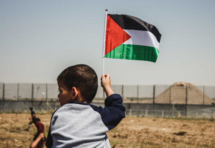 Child holding a Palestinian flag in an outdoor area