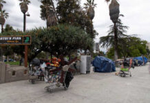 Homeless encampment with shopping carts and tents in a park