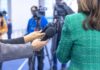 Hands holding microphones in front of a person at a press conference