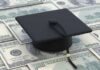 A graduation cap placed on a pile of hundred dollar bills