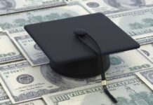 A graduation cap placed on a pile of hundred dollar bills