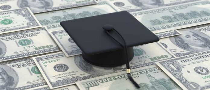 A graduation cap placed on a pile of hundred dollar bills