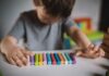 A child arranging colorful chalk sticks on a table