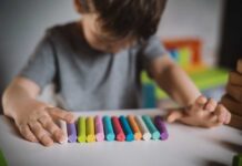 A child arranging colorful chalk sticks on a table