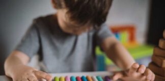 A child arranging colorful chalk sticks on a table