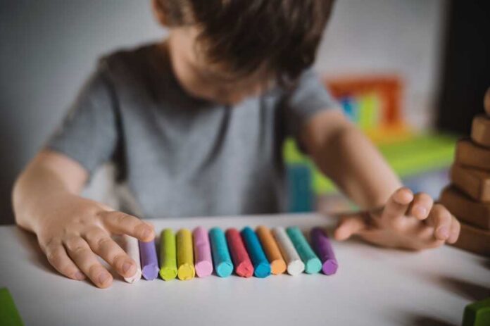 A child arranging colorful chalk sticks on a table