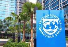 Qatar Sounds Alarm: Unseen Crisis Ahead! Sign of the International Monetary Fund in front of a modern building with palm trees
