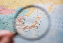 Japan’s RED AURORAS Warn of Space Storm Threats A magnifying glass focusing on a map of Japan