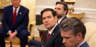 A serious-looking man in a suit sitting in a presidential office during a meeting
