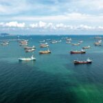 Aerial view of numerous cargo ships anchored in a blue ocean