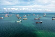 Aerial view of numerous cargo ships anchored in a blue ocean