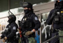 Minnesota’s Bold Move Against ICE Tactics Three police officers in riot gear standing guard outside a building