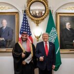 Two political leaders posing for a photo with flags in the background