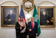 Two political leaders posing for a photo with flags in the background
