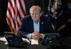 Trump Mediation Tested: Hezbollah Border Pressure Rises A serious-looking man seated at a table with phones and an American flag in the background