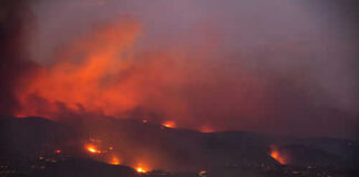 Wildfire lighting up the night sky over hills
