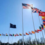 Flags of multiple countries against blue sky