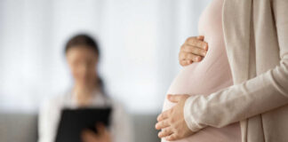 Pregnant person holding their belly during a medical visit