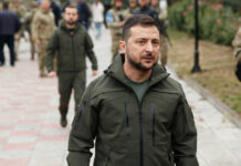 Zelensky walking outdoors with military personnel nearby.