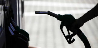 Silhouette of a hand holding a fuel nozzle at a gas station