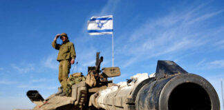 Soldier saluting from atop a tank with an Israeli flag in the background