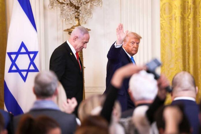 Man speaking in front of Israeli flag backdrop