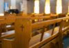 Catholic Activists Push Women’s Ordination in Spain — Church Holds Line Wooden church pew with carved cross in a sunlit sanctuary