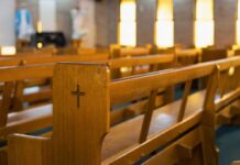 Wooden church pew with carved cross in a sunlit sanctuary