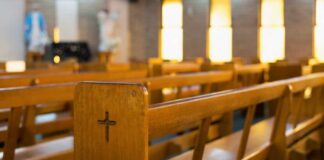 Wooden church pew with carved cross in a sunlit sanctuary