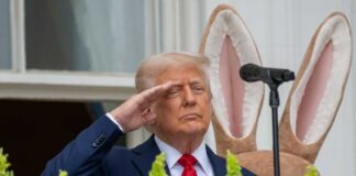 A man in a suit saluting in front of a floral display during an Easter event